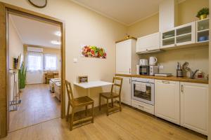 a kitchen with white cabinets and a table and chairs at Palmy Home Ecser in Ecser