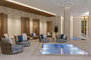 a hotel lobby with a swimming pool and chairs at Sheraton Uşak Hotel & Thermal Spa in Uşak