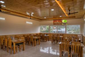 a dining room with wooden tables and chairs at Pacific Inn Vistaar Hotels & Resorts in Chamba