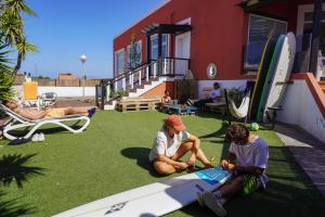a group of people sitting on the grass with surfboards at Banama Surfhouse - Coliving Coworking & Yoga in Corralejo +46 photos