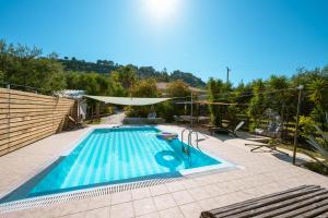 a swimming pool with an umbrella and a pool at Botonis Houses - Modern Villas, Timeless Beauty in Vasilikos