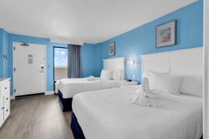 two beds in a hotel room with blue walls at Condos at the Caribbean Resort in Myrtle Beach