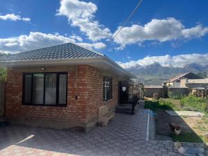 a small brick house with mountains in the background at Tunduk Guest House in Kochkorka