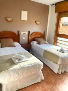 two beds sitting next to each other in a room at Hostal Bil in Salduero