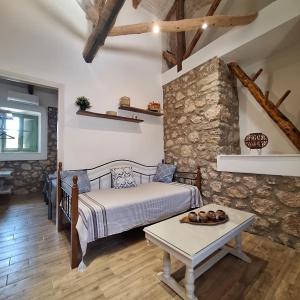 a bedroom with a bed and a table in a room at Alekos Cozy Stone 2BR Home Karya Center in Lefkada