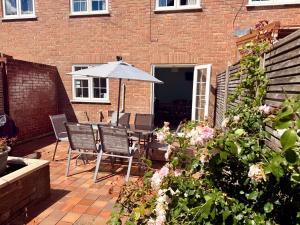 a patio with an umbrella and chairs and flowers at Bayfields house by the Sea, parking, garden, central location in Portsmouth