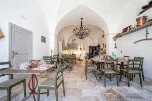 a dining room with tables and chairs and a chandelier at Masseria Lamapecora in Faccia di Trippa