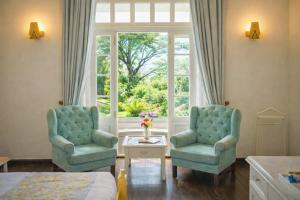 two chairs and a table in a room with a window at Pine Retreat - A Premium Heritage Property in Mussoorie