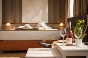 a hotel room with a bed and a table with wine glasses at Hotel Apoksiomen in Mali Lošinj
