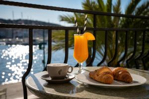 a table with a plate of croissants and a glass of orange juice at Hotel Apoksiomen in Mali Lošinj