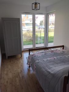 a bedroom with a bed and large windows at Nowoczesny Apartament 400 M Od Plaży Prywatny Ogródek Ełk in Ełk