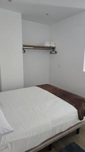 a bed with white sheets and a shelf on the wall at Loft Casco Viejo 4 in Ourense +12 photos