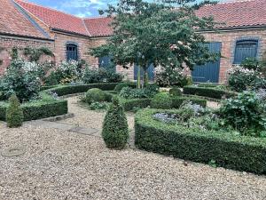 a garden with bushes and trees and a building at Black Drove Farm in Twenty