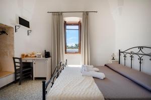 a bedroom with a bed and a desk and a window at Masseria Lamapecora in Faccia di Trippa