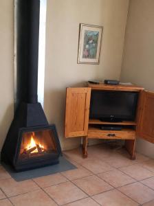 a fireplace in a living room with a television and a stove at Alpha Self-Catering in Sutherland