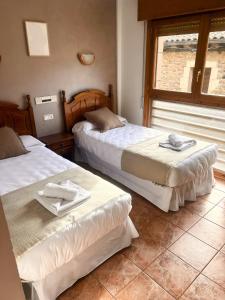 two beds sitting in a room with a window at Hostal Bil in Salduero