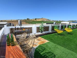 a patio with chairs and a wooden table and grass at בקתות לוטן דלתון - 4 בקתות עם ג'קוזי פרטי ו-2 בריכות משותפות in Shahar