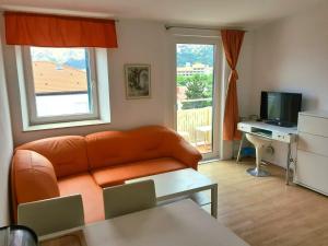 a living room with an orange couch and a television at Apartments Eis in Baška