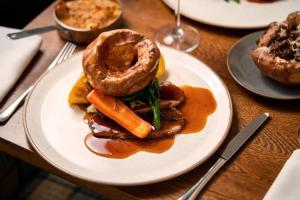 a plate of food with a donut and carrots on a table at The Cherry Tree Rochford in Rochford
