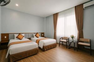 a hotel room with two beds and a desk at Eagle Sầm Sơn Hotel in Sầm Sơn