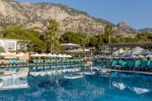 a swimming pool with chairs and mountains in the background at Crystal Flora Pearl Collection - Ultimate All Inclusive in Beldibi