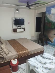 a bedroom with a bed and a flat screen tv at hotel shaurya in Naroda