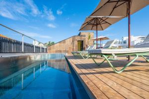 a deck with a chaise lounge and an umbrella next to a pool at Terreno Barrio Hotel in Palma de Mallorca