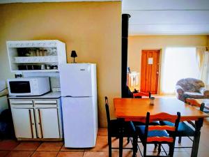 a kitchen with a table and a white refrigerator at Alpha Self-Catering in Sutherland