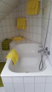 ein Badezimmer mit einer Badewanne und gelben Handtüchern in der Unterkunft Hotel Neuner in München