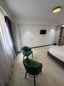 a bedroom with a bed and two green chairs at Iconic Coworking Hotel in Addis Ababa