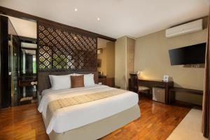 a bedroom with a large bed and a flat screen tv at The Sterling Villas in Uluwatu