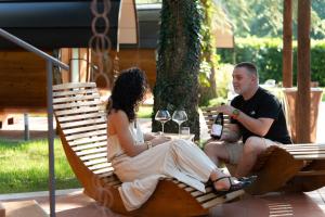 a man and a woman sitting on a swinging chair at Rifugio diVino Dormire in una botte - Wine Barrel stay near Rome in Rieti