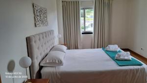 a bedroom with a large white bed with towels on it at Apartamento Lombinha in Vila Franca do Campo