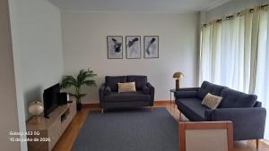 a living room with two blue couches and a tv at Apartamento Lombinha in Vila Franca do Campo