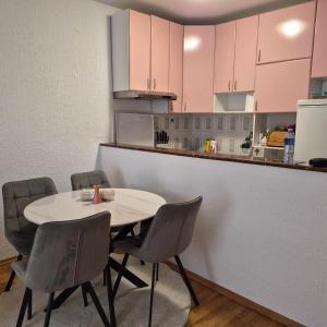 a table and chairs in a kitchen with pink cabinets at Bright & Spacious Apartment Budva in Budva +3 photos