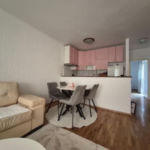 a living room with a table and chairs and a kitchen at Bright & Spacious Apartment Budva in Budva