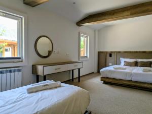 a large bedroom with two beds and a mirror at AMZA Valbona Mountain Retreat in Valbonë