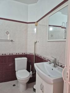 a bathroom with a white toilet and a sink at Хотел М in Asenovgrad