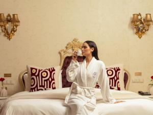 a woman in a robe sitting on a bed at Art Palace Suites & Spa in Casablanca