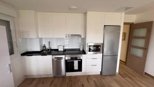 a kitchen with white cabinets and a stainless steel refrigerator at AuraGalega Noro in Ribeira