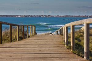 a wooden boardwalk leading to the ocean on a beach at AuraGalega Noro in Ribeira +4 photos