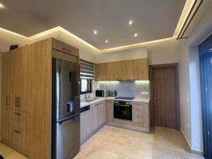 a kitchen with wooden cabinets and a stainless steel refrigerator at Ionian Waves Villa - Marathopoli Stylish Escape in Marathopoli