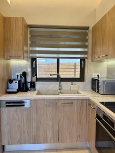 a kitchen with wooden cabinets and a sink and a window at Ionian Waves Villa - Marathopoli Stylish Escape in Marathopoli