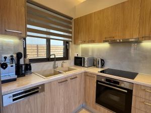 a kitchen with wooden cabinets and a sink and a microwave at Ionian Waves Villa - Marathopoli Stylish Escape in Marathopoli +33 photos