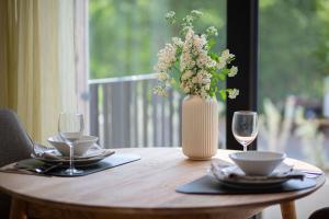 a table with a vase of flowers and two glasses at Luxus-Ferienwohnung DS11 in Fehmarn