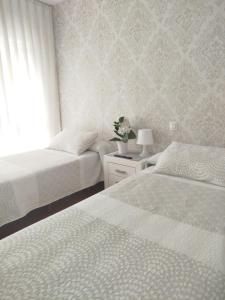 a bedroom with two beds and a window at Pensión Vegadeo GIJÓN in Gijón