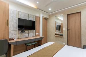 a hotel room with a bed and a flat screen tv at Hotel Ashish in Ahmedabad
