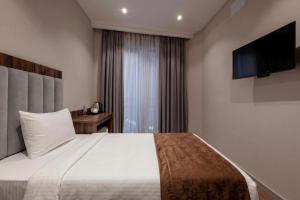 a hotel room with a bed and a flat screen tv at White Hill Hotel in Tbilisi City