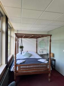a bedroom with a wooden canopy bed in a room at Het Huis van Bewustzijn in Limmen