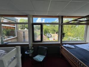 a bedroom with windows and a bed and a chair at Het Huis van Bewustzijn in Limmen +182 photos